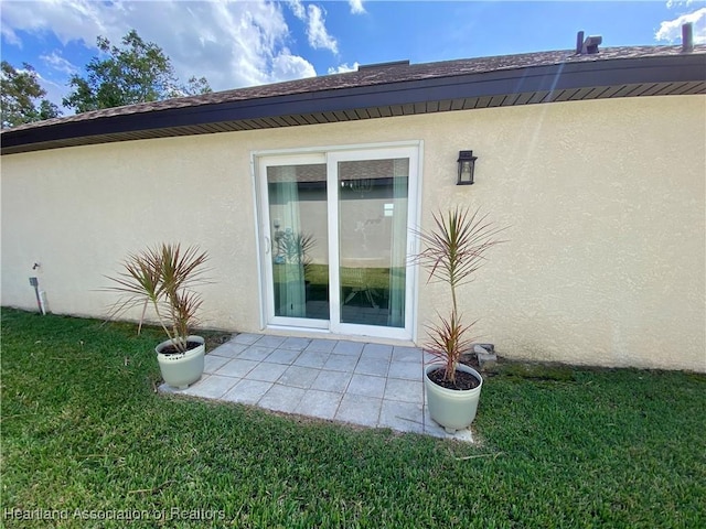view of side of property featuring a patio, a lawn, and stucco siding
