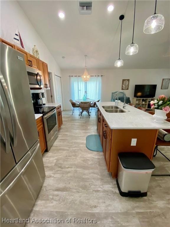 kitchen featuring brown cabinets, light countertops, visible vents, appliances with stainless steel finishes, and a sink