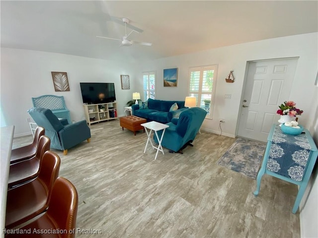 living area featuring wood finished floors, a ceiling fan, and baseboards
