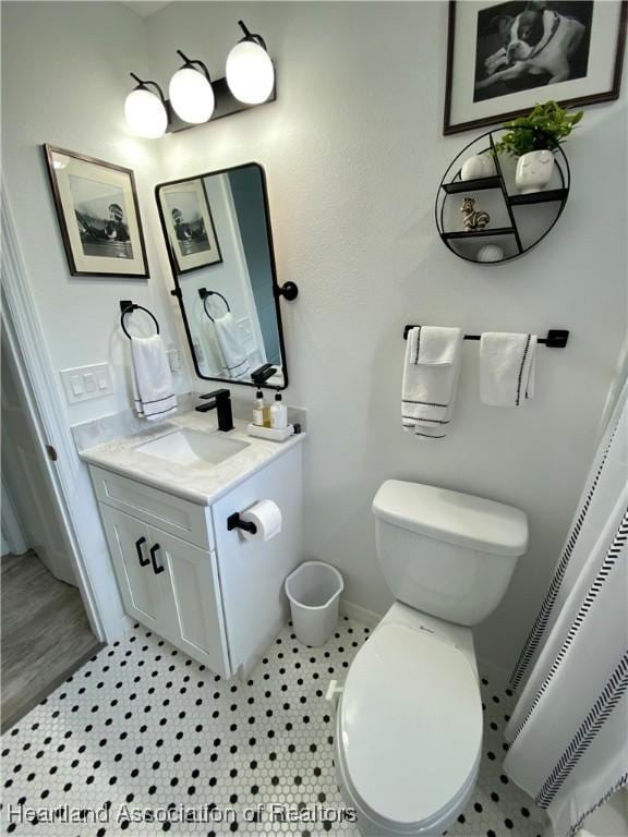 bathroom with baseboards, vanity, and toilet