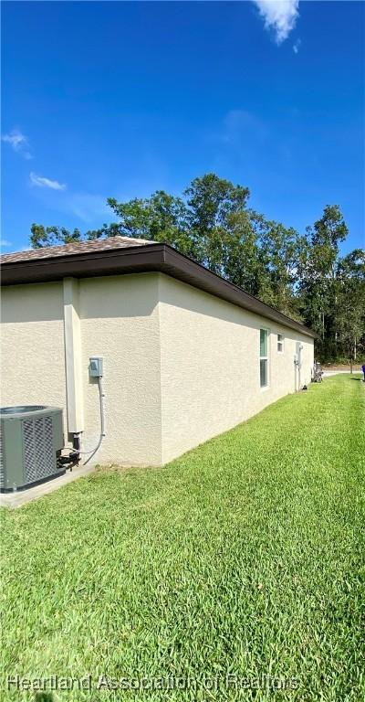 view of property exterior featuring a yard, central AC unit, and stucco siding