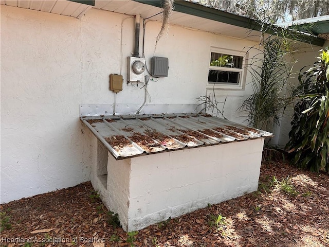 exterior details featuring electric meter and stucco siding