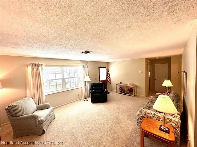 living area with baseboards, carpet flooring, a textured ceiling, and visible vents