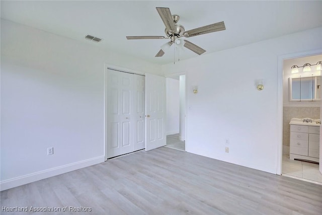 unfurnished bedroom with connected bathroom, a closet, wood finished floors, and visible vents