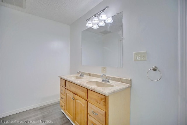 full bath with visible vents, a sink, wood finished floors, and double vanity