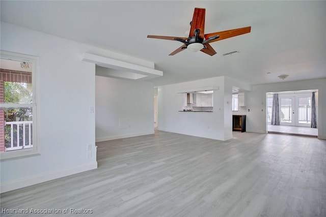 unfurnished living room featuring a healthy amount of sunlight, ceiling fan, light wood-style floors, and visible vents
