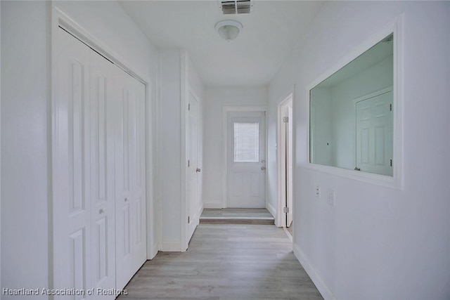 hallway featuring baseboards, visible vents, and light wood-style flooring