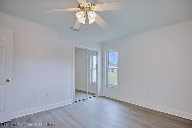 unfurnished bedroom featuring a ceiling fan, baseboards, wood finished floors, and a closet