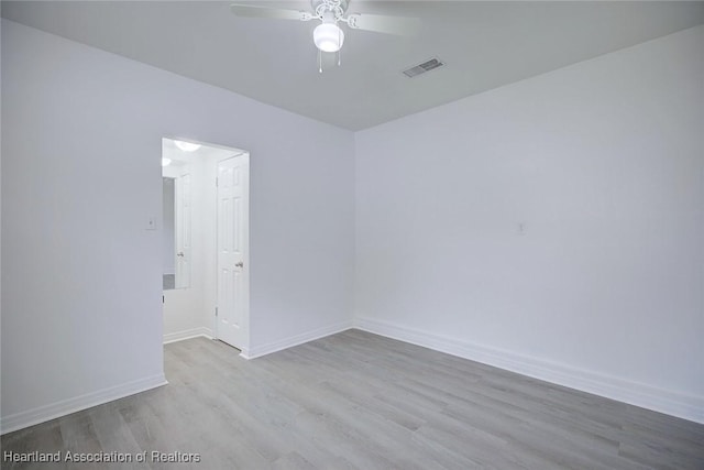 unfurnished room with baseboards, a ceiling fan, wood finished floors, and visible vents