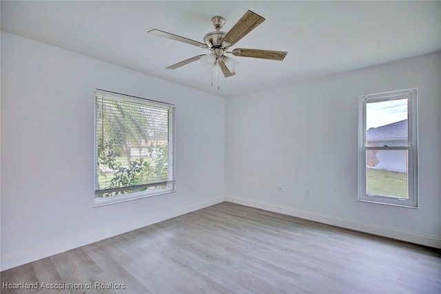 spare room with baseboards, ceiling fan, and wood finished floors