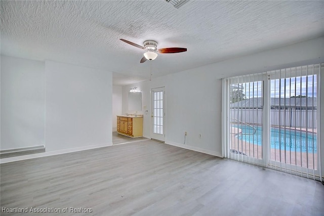 spare room with baseboards, ceiling fan, a textured ceiling, and wood finished floors