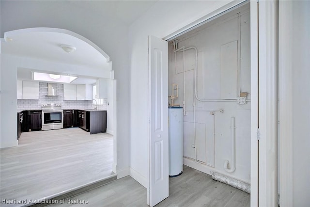 bathroom featuring wood finished floors, baseboards, a sink, water heater, and backsplash
