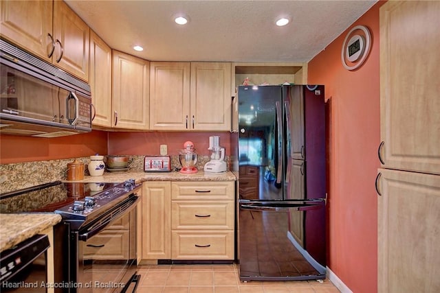 kitchen with light tile patterned floors, light brown cabinets, light stone counters, and black appliances