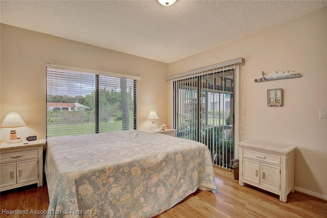 bedroom featuring access to outside, a textured ceiling, and light wood-type flooring