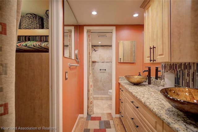 bathroom featuring toilet, vanity, and tiled shower