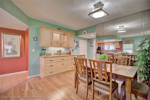 dining area with a textured ceiling and light wood-type flooring