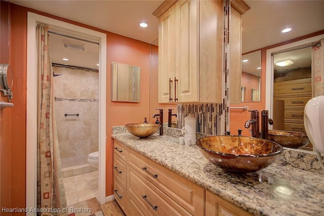 bathroom with tiled shower, vanity, and toilet