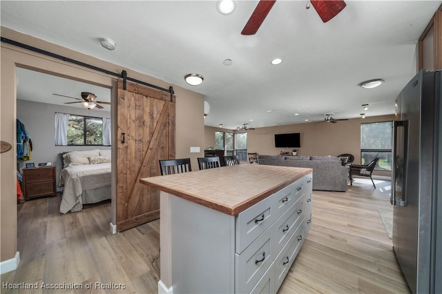 kitchen featuring a barn door, stainless steel fridge, light hardwood / wood-style floors, and a wealth of natural light