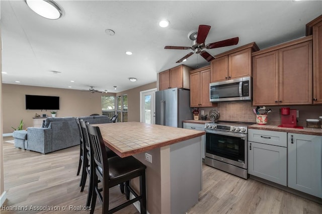 kitchen featuring a kitchen breakfast bar, tasteful backsplash, stainless steel appliances, tile countertops, and a center island