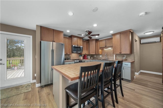 kitchen featuring a center island, a kitchen breakfast bar, a wall unit AC, decorative backsplash, and appliances with stainless steel finishes