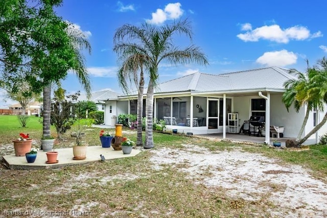 rear view of property featuring a sunroom and a patio area