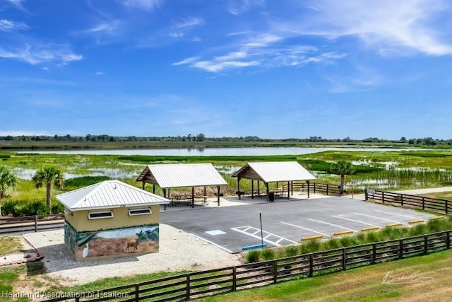 view of community featuring uncovered parking, an enclosed area, and a water view