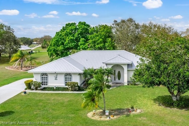 view of front of home with a front yard, a standing seam roof, metal roof, and driveway