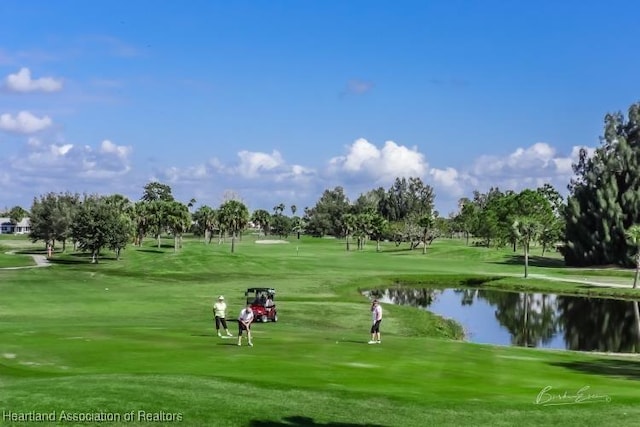 view of community featuring view of golf course, a water view, and a lawn