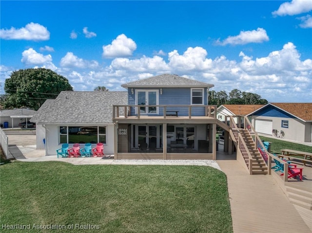 rear view of house featuring stairs, a balcony, a shingled roof, a lawn, and a sunroom