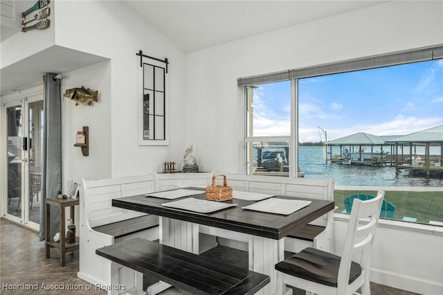 dining room featuring a barn door, a water view, and lofted ceiling
