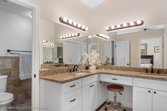 bathroom with vanity, toilet, and tile walls