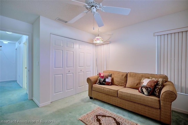 living room featuring visible vents, a ceiling fan, and carpet