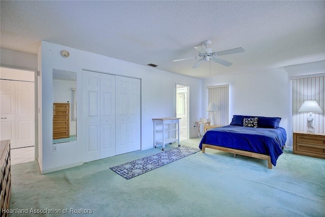 carpeted bedroom featuring a ceiling fan, a closet, a textured ceiling, and visible vents