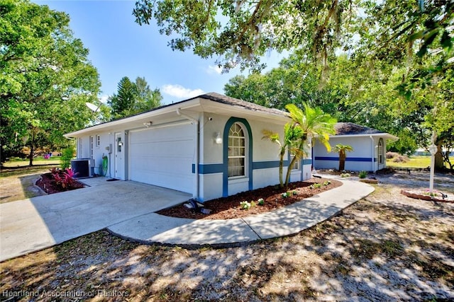 view of front of home featuring concrete driveway, an attached garage, cooling unit, and stucco siding