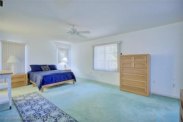 carpeted bedroom with visible vents, a ceiling fan, baseboards, and a textured ceiling