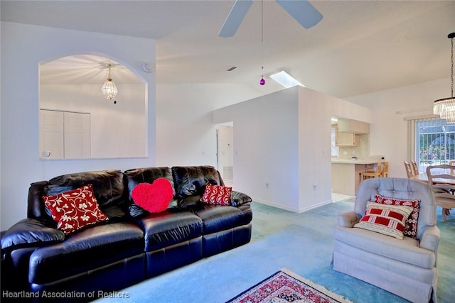living room with arched walkways, baseboards, ceiling fan with notable chandelier, lofted ceiling, and carpet
