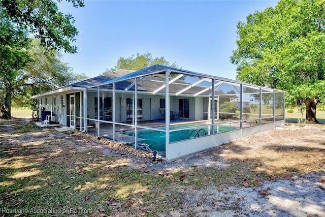 back of house featuring glass enclosure and an outdoor pool