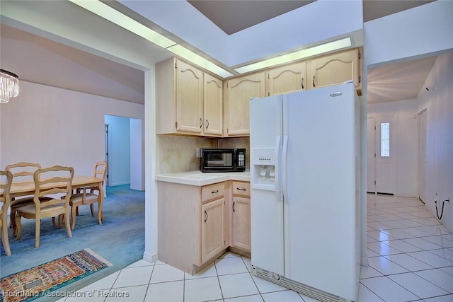 kitchen with light countertops, light tile patterned floors, white refrigerator with ice dispenser, and backsplash