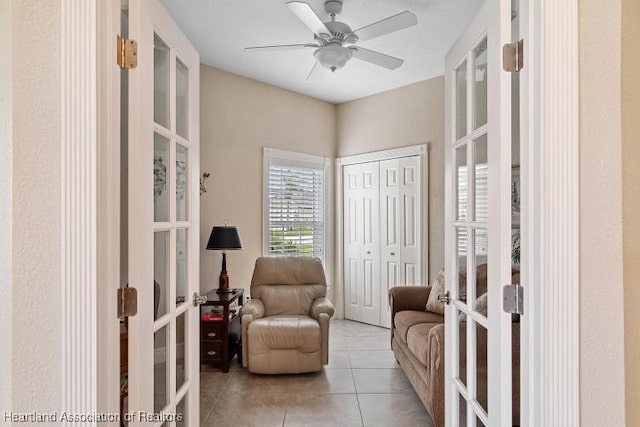 sitting room featuring ceiling fan, french doors, and light tile patterned floors