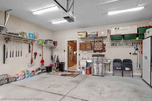 garage with stainless steel fridge with ice dispenser, a garage door opener, and sink