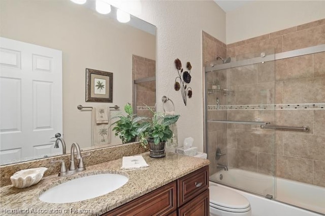 full bathroom with shower / bath combination with glass door, vanity, and toilet