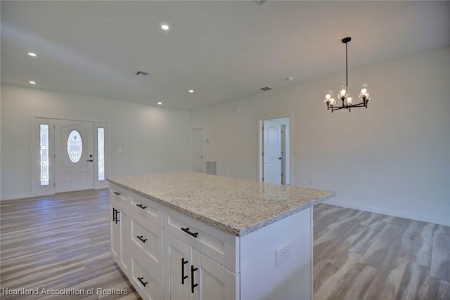 kitchen featuring white cabinets, a notable chandelier, light hardwood / wood-style floors, and light stone counters