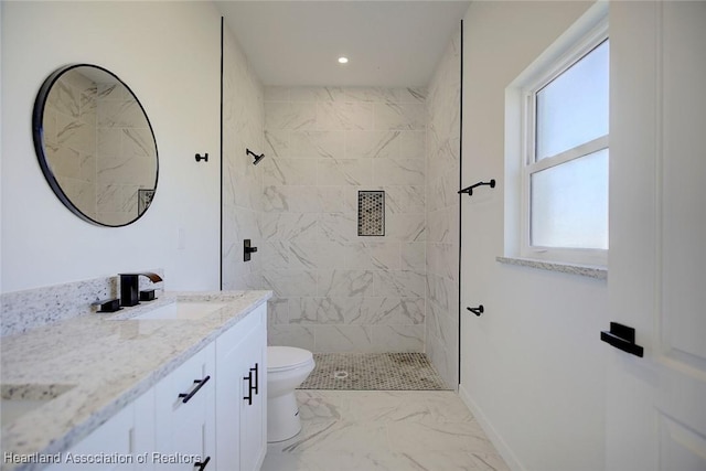 bathroom featuring vanity, toilet, and a tile shower