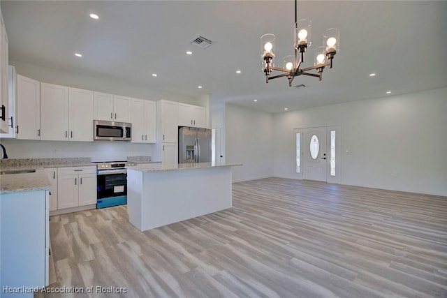 kitchen featuring white cabinetry, stainless steel appliances, pendant lighting, light hardwood / wood-style floors, and a kitchen island