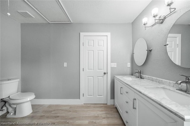 bathroom featuring vanity, toilet, wood-type flooring, and a textured ceiling