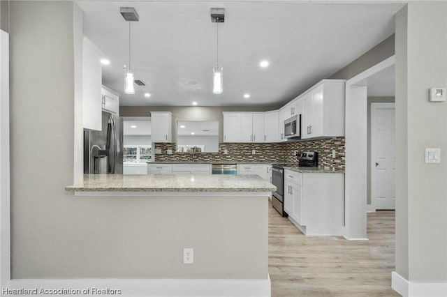 kitchen with light stone countertops, kitchen peninsula, decorative light fixtures, white cabinets, and appliances with stainless steel finishes