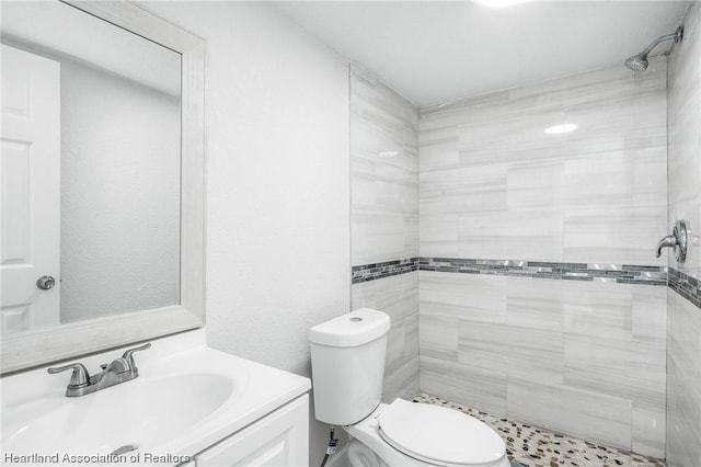 bathroom featuring vanity, toilet, and a tile shower