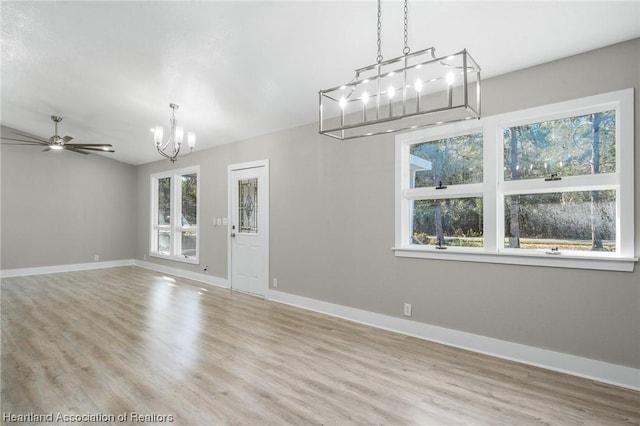 interior space with ceiling fan with notable chandelier and light hardwood / wood-style flooring