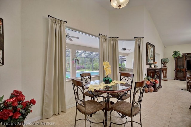 tiled dining space with ceiling fan and high vaulted ceiling