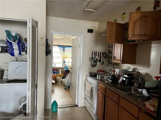 kitchen featuring white range with electric cooktop, washer / clothes dryer, sink, and light tile patterned floors